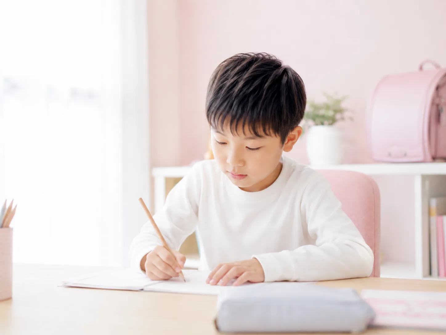 机に向かって集中して勉強するお子さま
