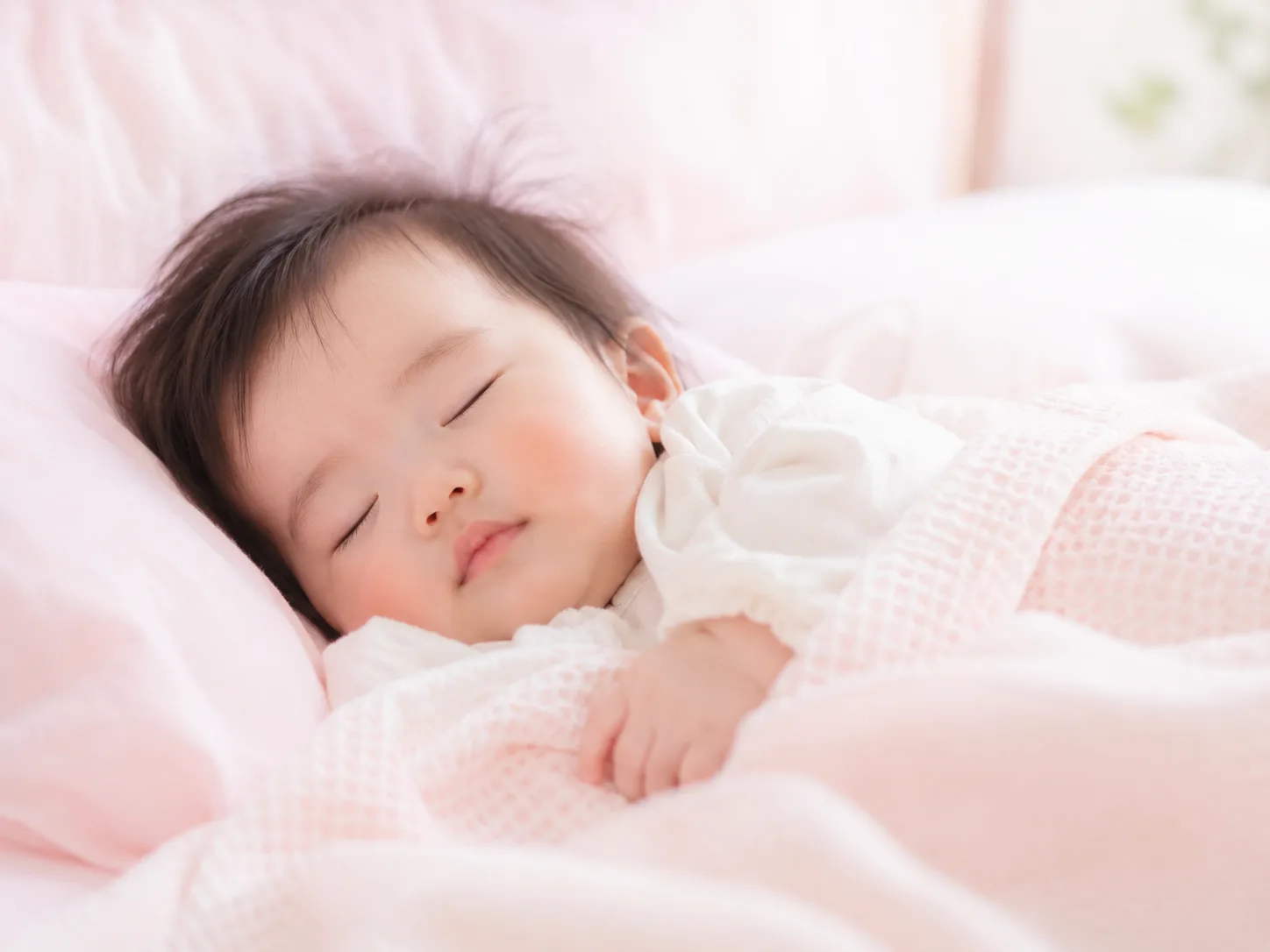 ピンクの布団で穏やかに眠るお子さま